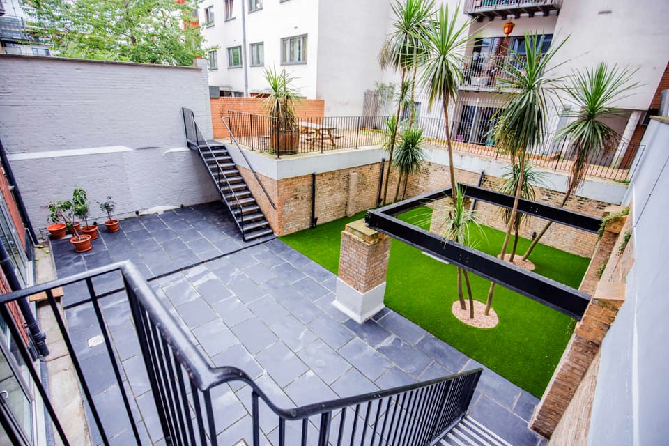 The courtyard behind the building, with palms and a picnic table on the terrace above