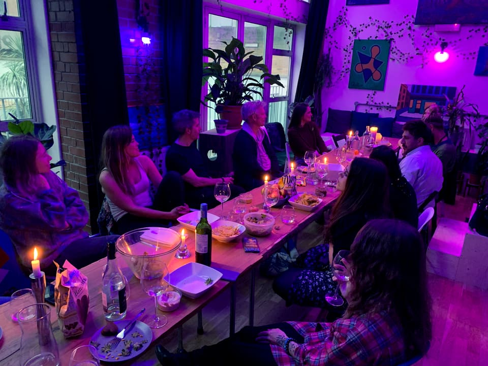A long candlelit table set for a community dinner