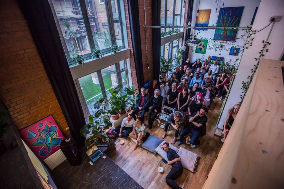 A full audience seated for a talk in the double-height room