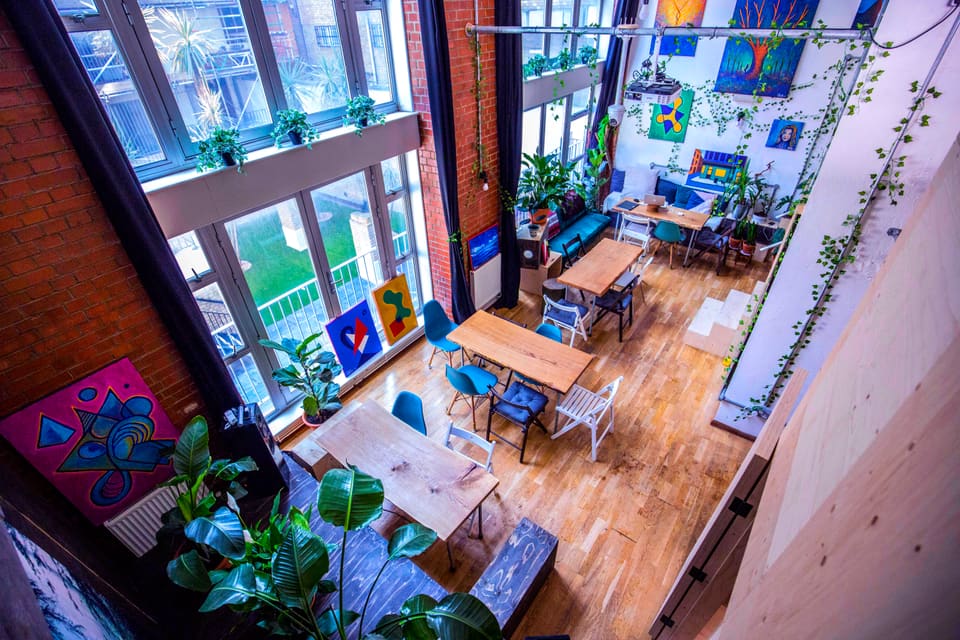 Cafe tables and chairs set out beside the tall windows