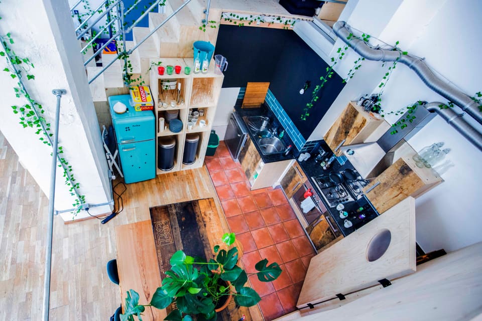 The kitchen, with terracotta tiles, a teal fridge and large plants