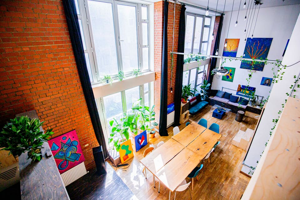 Long wooden table set for a workshop beside the double-height warehouse windows