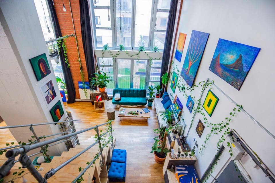 The main room with paintings, plants and the teal sofa, empty and ready